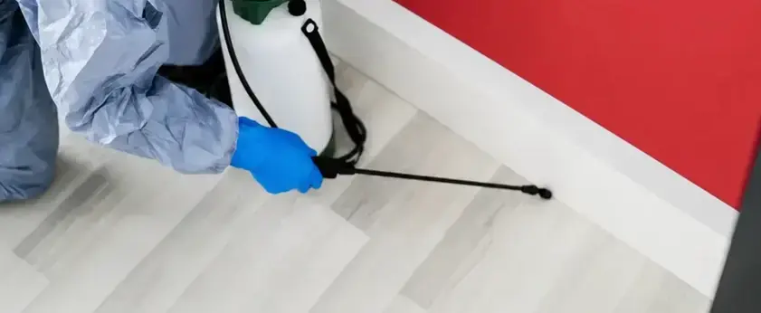Brice Pest Control technician applying cockroach treatment along a baseboard in a West Jordan, UT home